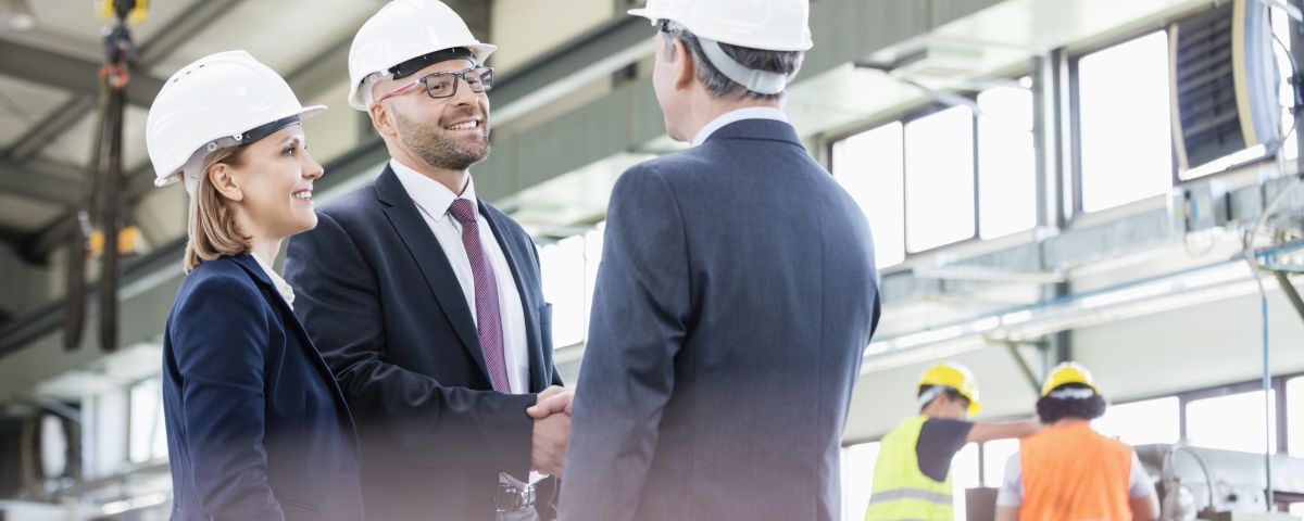 Führungskräfte schütteln Hände in Industriehalle zum Innovationerfolg - TOM SPIKE