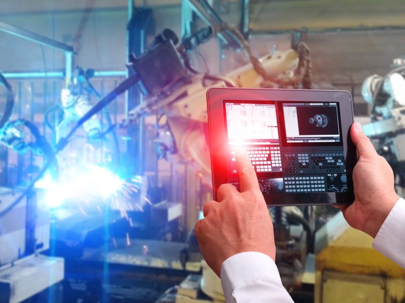 Touchpad Display in front of flashing manufacturing system as a symbol for Product Innovation - TOM SPIKE