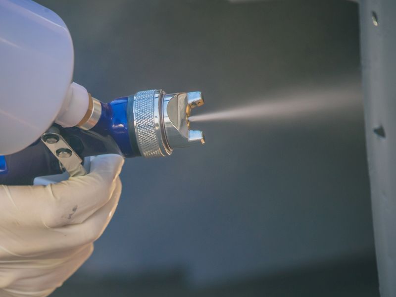 Painter sprays paint with compressed air as a symbol of business model innovation - TOM SPIKE