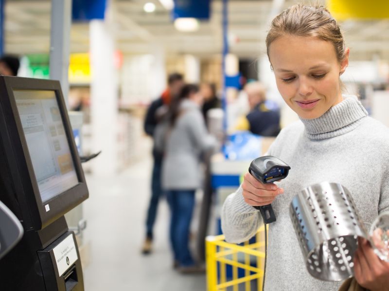 Buyer scans the product at the self-service checkout as a symbol of service innovation - TOM SPIKE