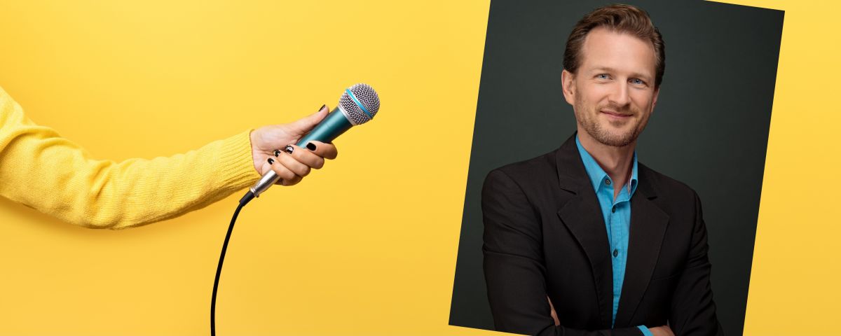 Innovationsberater Henryk Stöckert am Mikrofon vor gelbem Hintergrund - TOM SPIKE