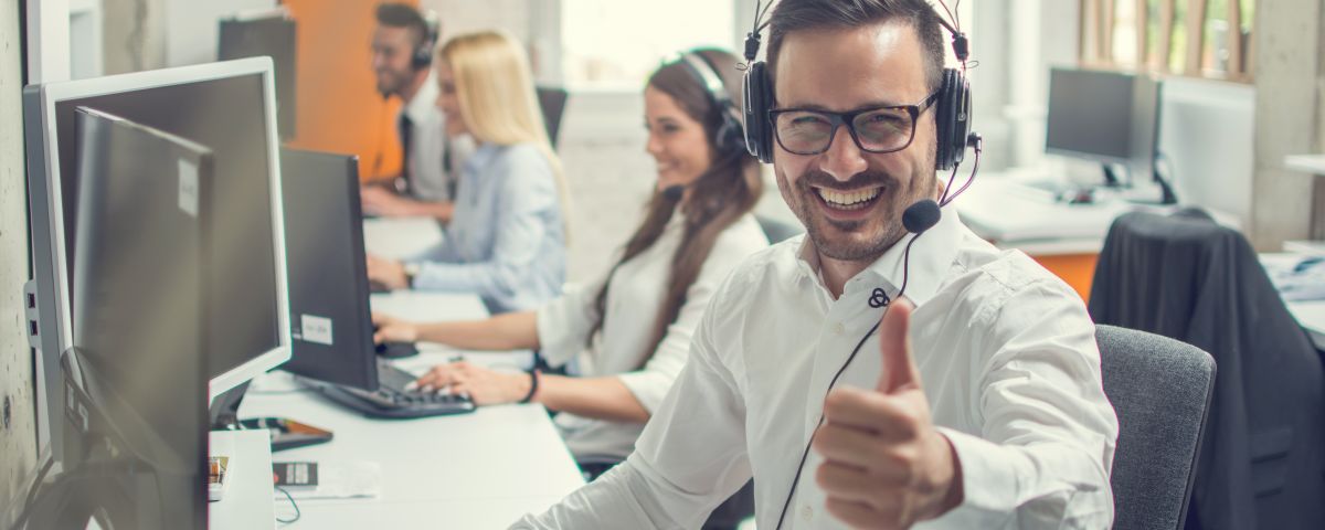 Friendly male helpline operator man with headphones showing thum Innovationsberater mit Headset zeigt Daumen hoch - TOM SPIKE