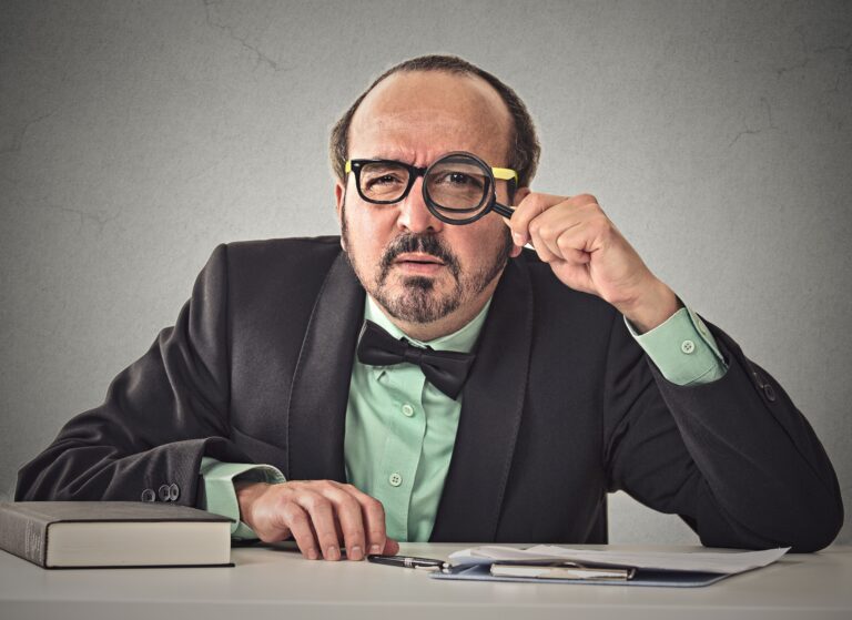 Controller mit Kragen, Fliege und Lupe als Symbol für die Effizienzfalle - TOM SPIKE Structured innovation