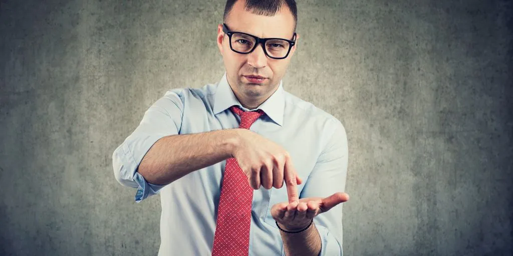 Verärgerter Controller zeigt mit dem Finger auf seine Handfläche und ist unzufrieden mit Innovation weil keine Ergebnisse geliefert werden - TOM SPIKE