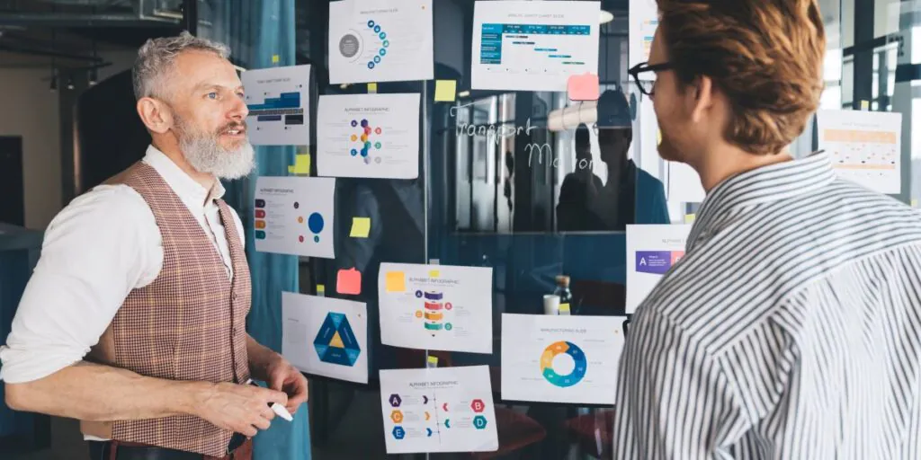 Geschäftsführung und Innovationsmanager bewerten Konzepte und Ideen vor ausgedruckten Charts - TOM SPIKE
